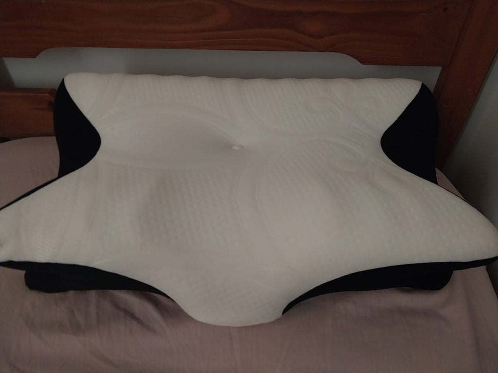 Contoured white and black memory foam pillow on a bed