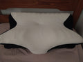 Contoured white and black memory foam pillow on a bed