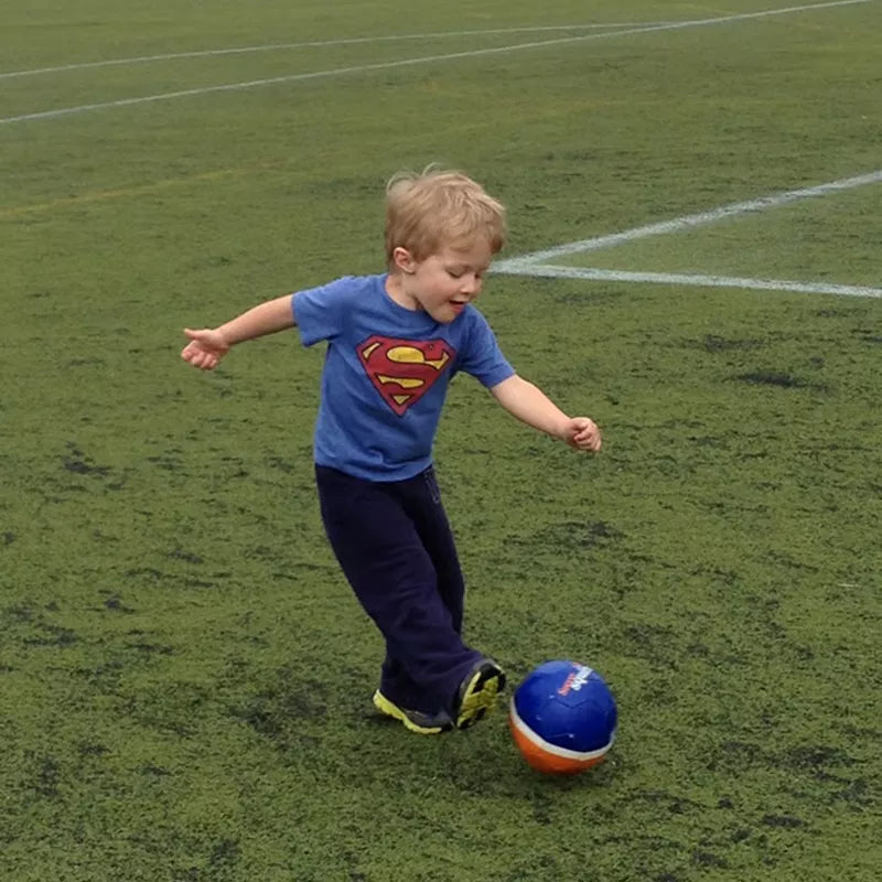 Toddler kicking a ball on a sports field