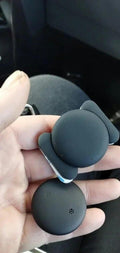 Tracker tag and its protective sleeve held in a hand inside a car