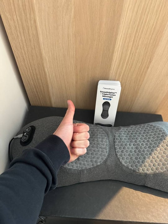 Massager resting on a chair with a thumbs-up from its owner