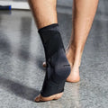 Black compression foot sleeve worn on a bare foot, seen from behind