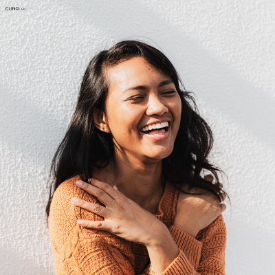 Smiling woman with her hand on her shoulder