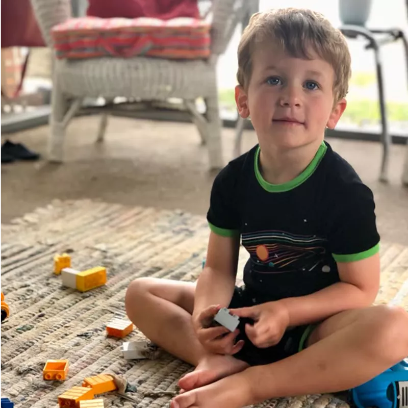 Young boy playing with building blocks on a rug