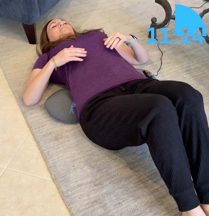 Woman lying on a rug with the massager under her lower back