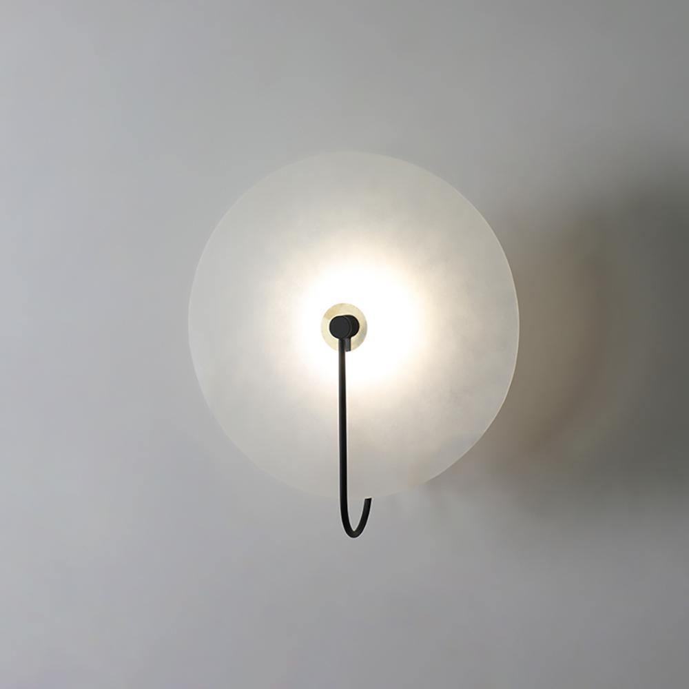 Kristy LED-vägglampa i alabaster — runt snöflingemönster, smal svart arm