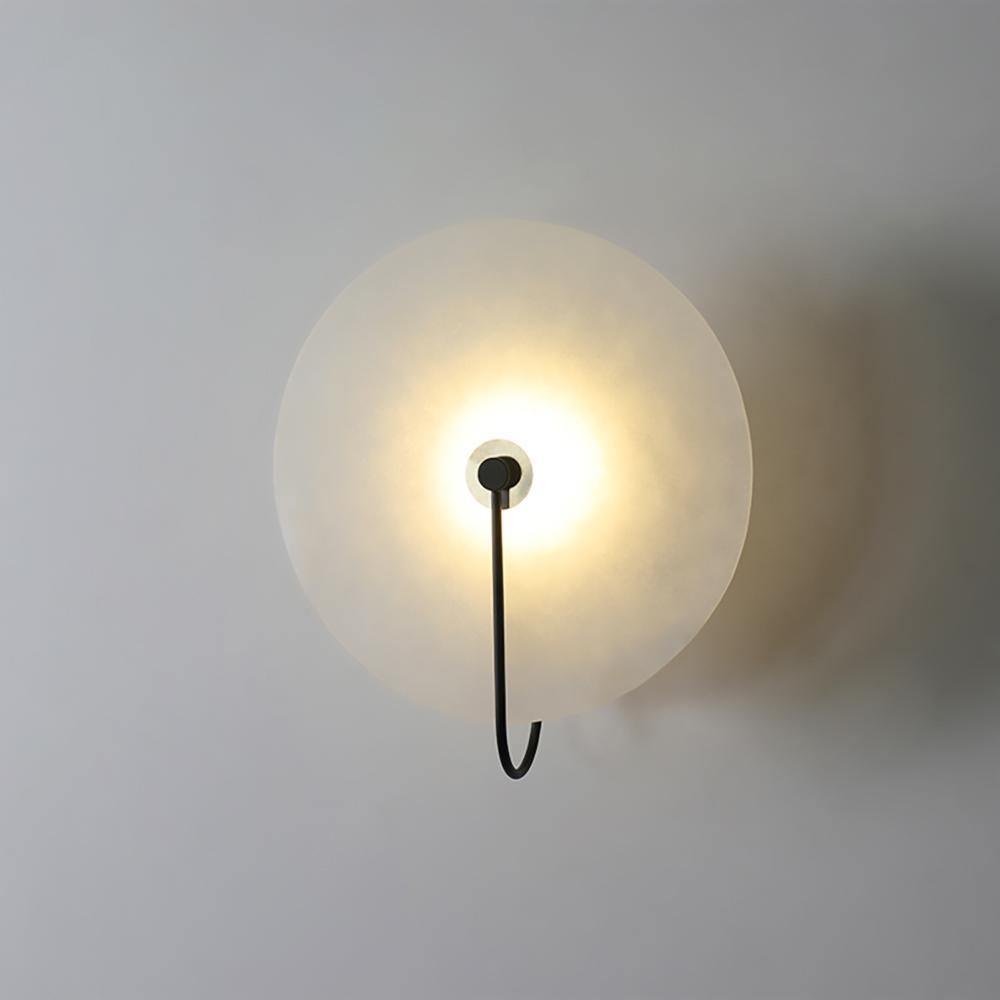 Kristy LED-vägglampa i alabaster — runt snöflingemönster, smal svart arm