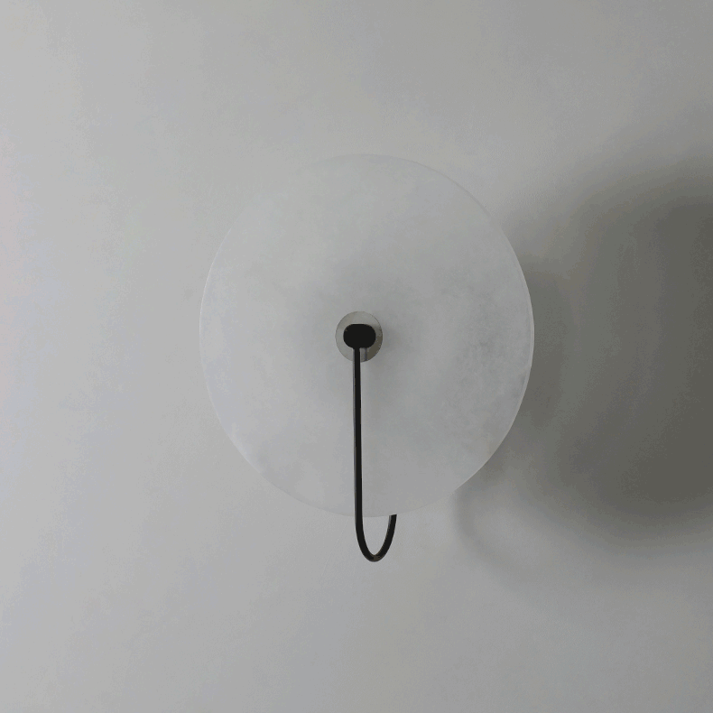 Kristy LED-vägglampa i alabaster — runt snöflingemönster, smal svart arm