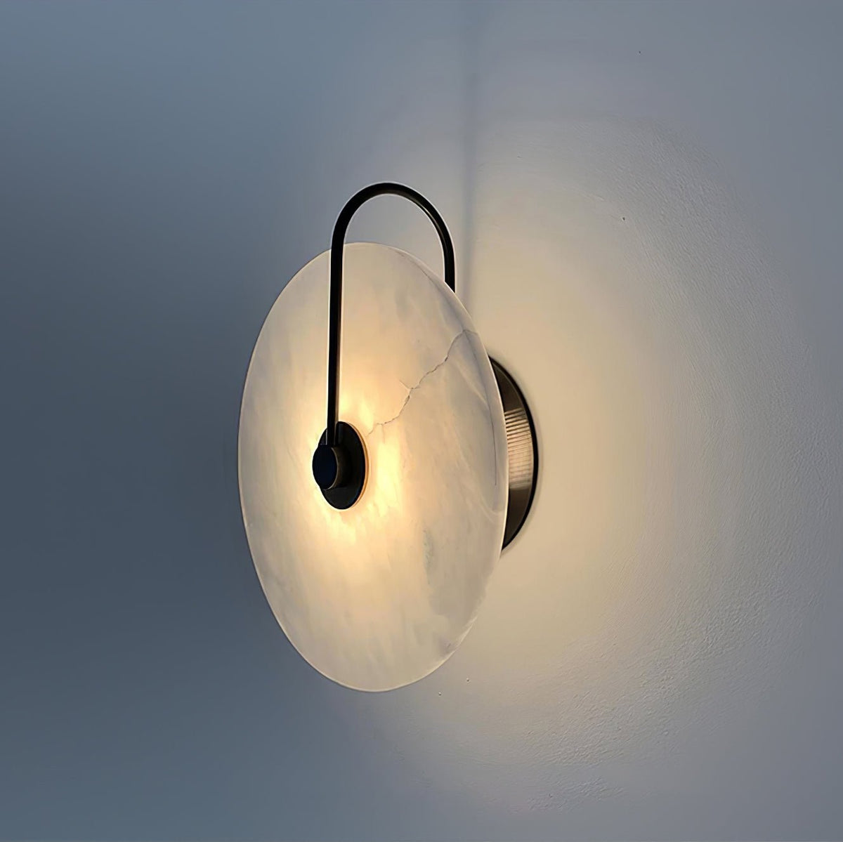 Kristy LED-vägglampa i alabaster — runt snöflingemönster, smal svart arm