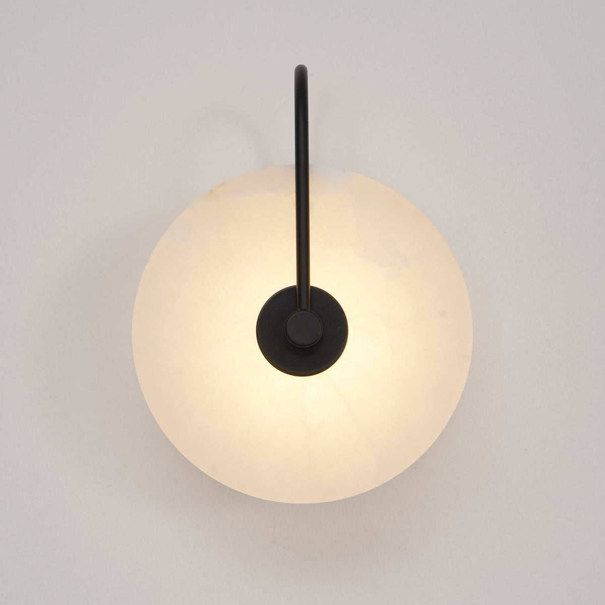 Kristy LED-vägglampa i alabaster — runt snöflingemönster, smal svart arm