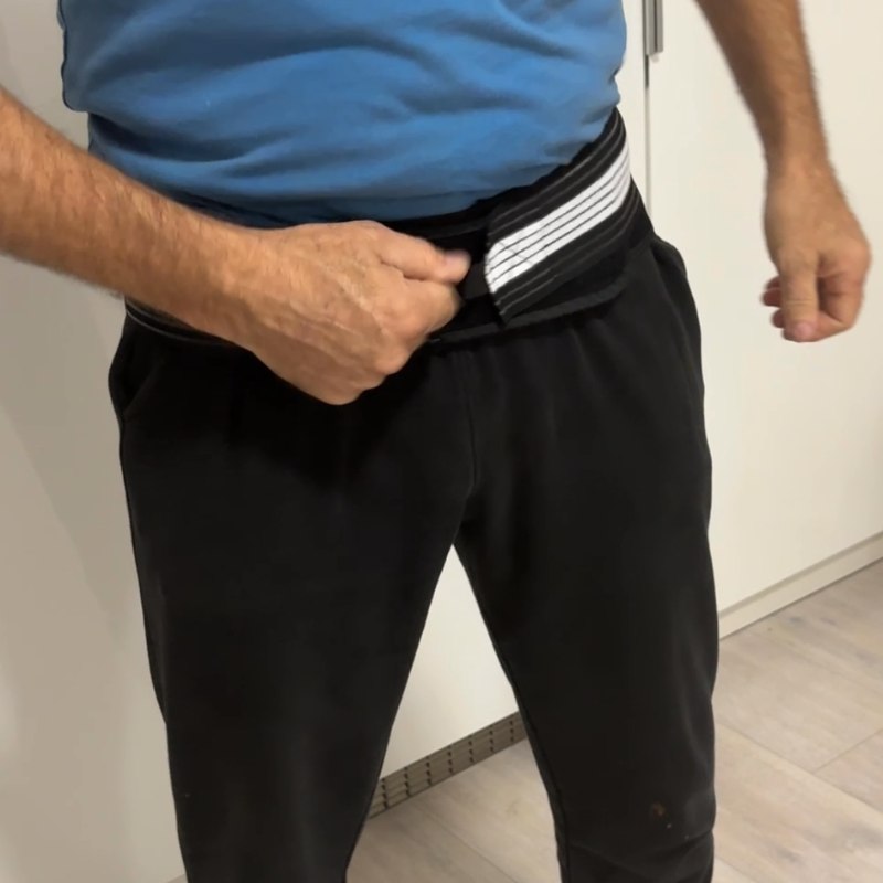 Man adjusting the hip belt around his pelvis while standing