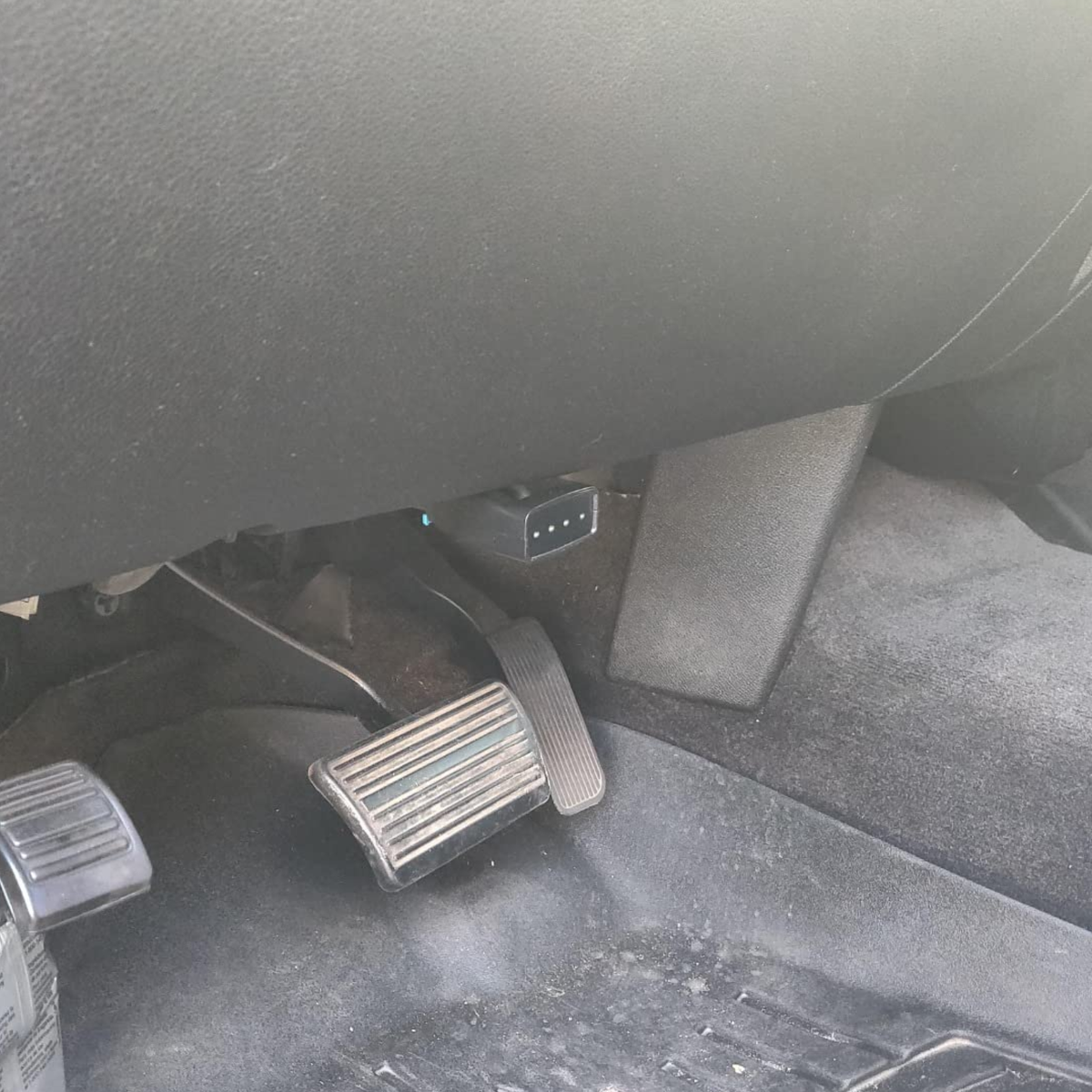 Area under the driver's side dashboard above the pedals where the OBD-II port is located