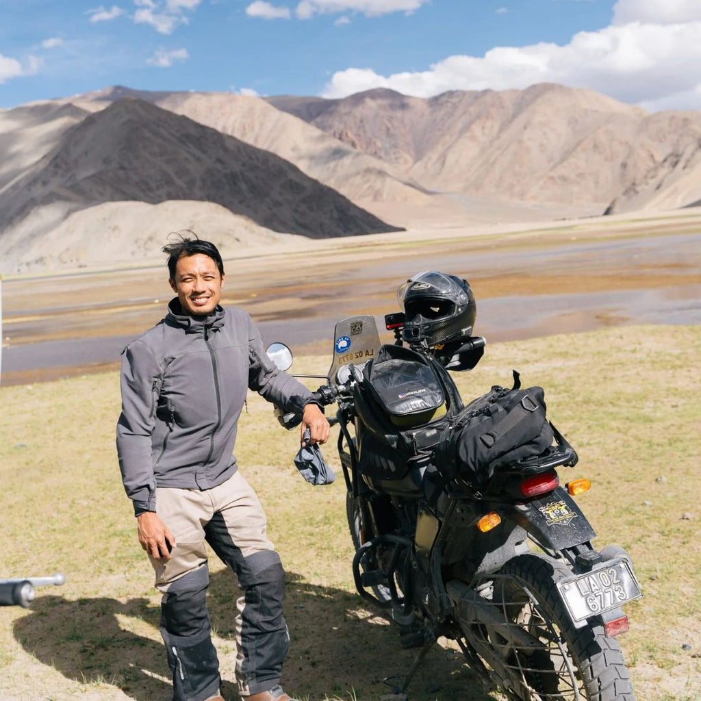 Rider standing next to his motorcycle in a mountain landscape