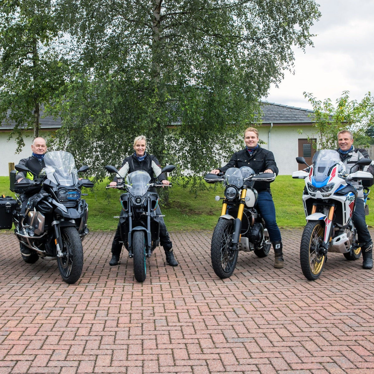 Group of four riders standing next to their motorcycles