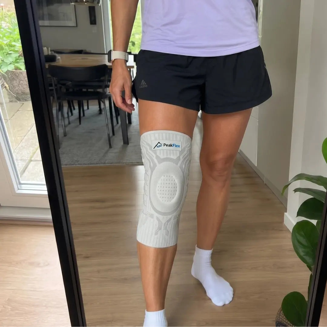 Woman in shorts wearing the knee sleeve in front of a mirror at home