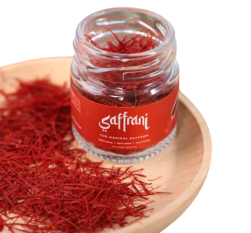 Open jar of saffron on a wooden plate covered in threads