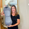 Smiling woman at home holding the grey contoured back massager