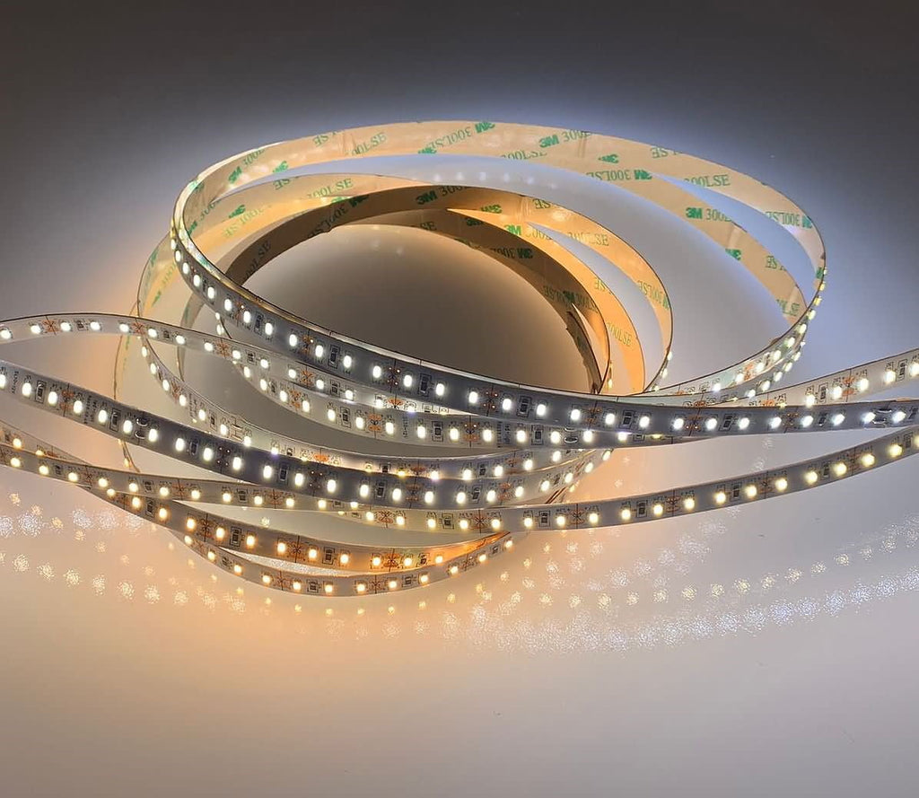Coiled adhesive LED light strip glowing warm white