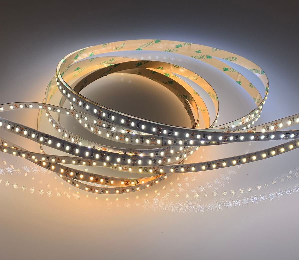 Coiled adhesive LED light strip glowing warm white