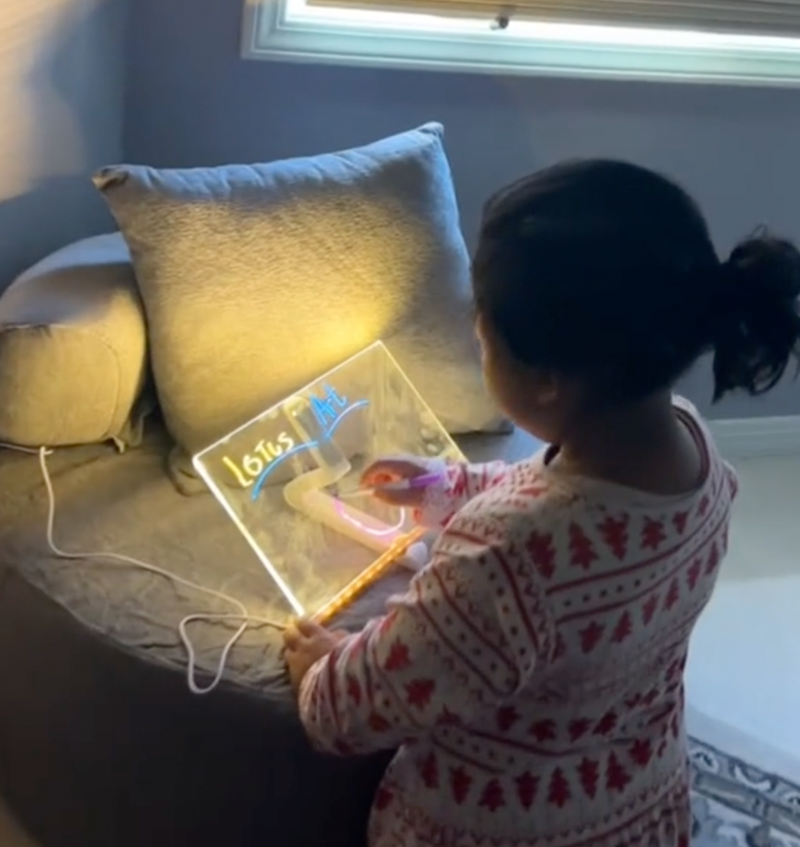 Child writing on the glowing board on a sofa