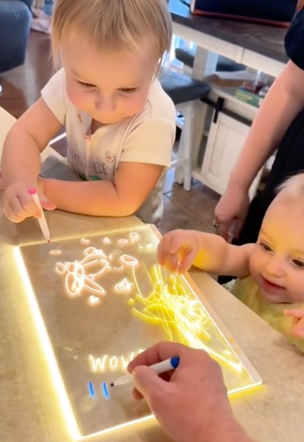 Parent and two small children drawing together on the board