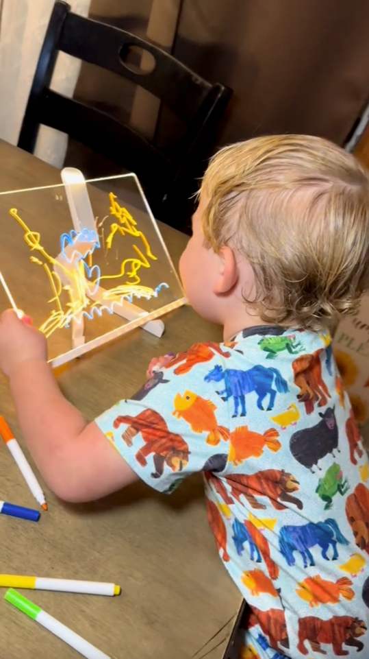 Toddler drawing on the glowing board at the kitchen table