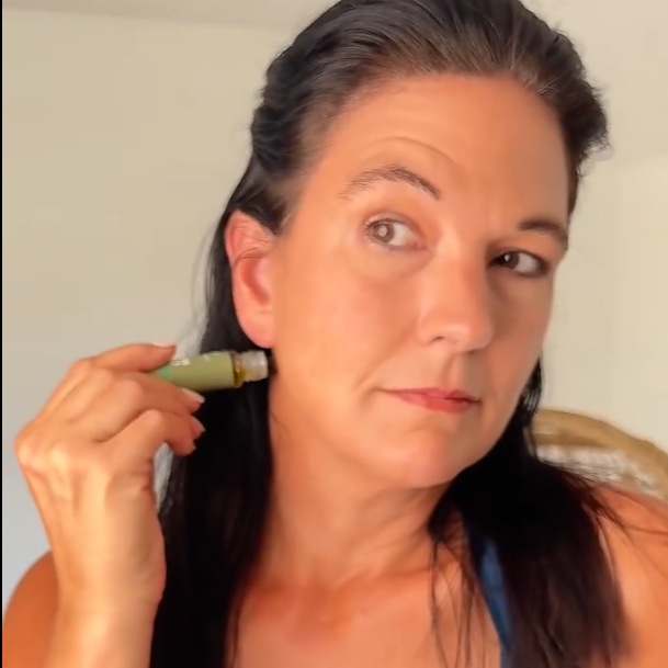 Woman rolling the oil blend onto her temple at home