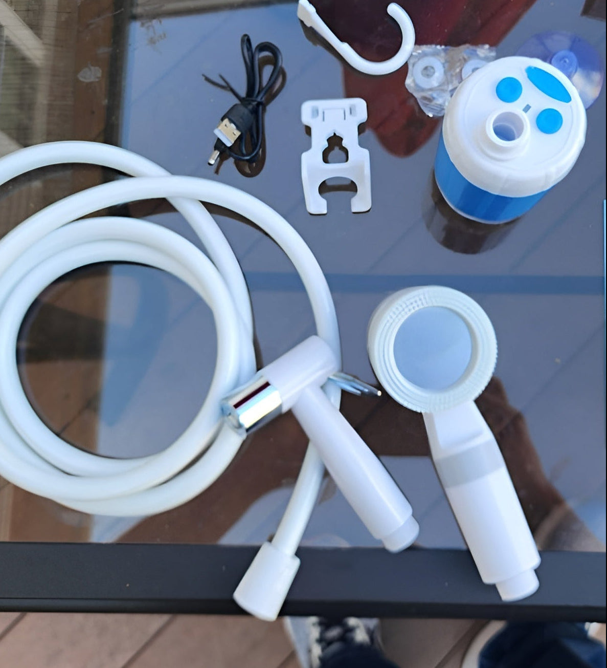 Kit contents laid out: pump, hose, shower head, mount and charging cable
