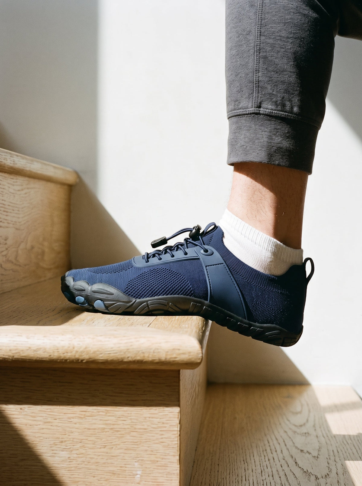 Midnight blue barefoot shoe stepping onto a wooden stair
