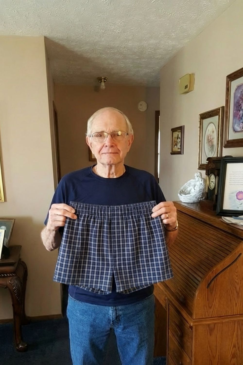 Older man at home holding up a pair of navy plaid boxers