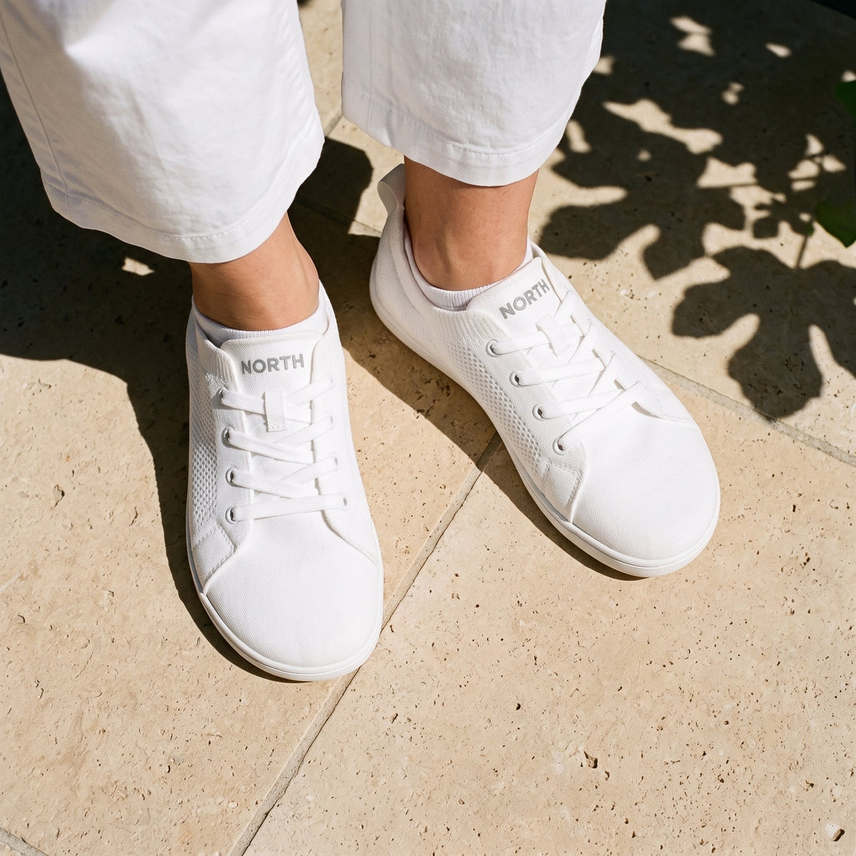 Feet in white sneakers on a sunny stone terrace