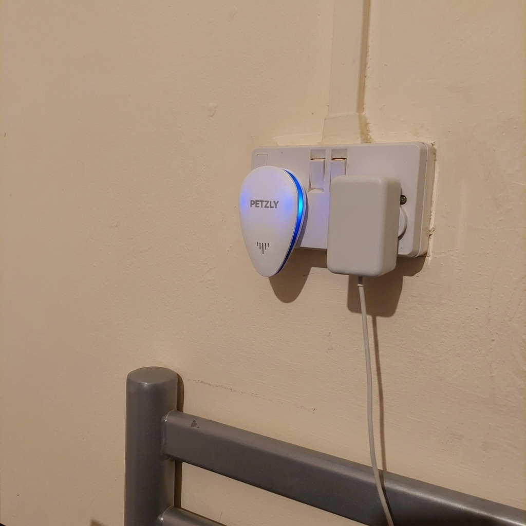 Repeller plugged into a double wall socket beside a bed frame