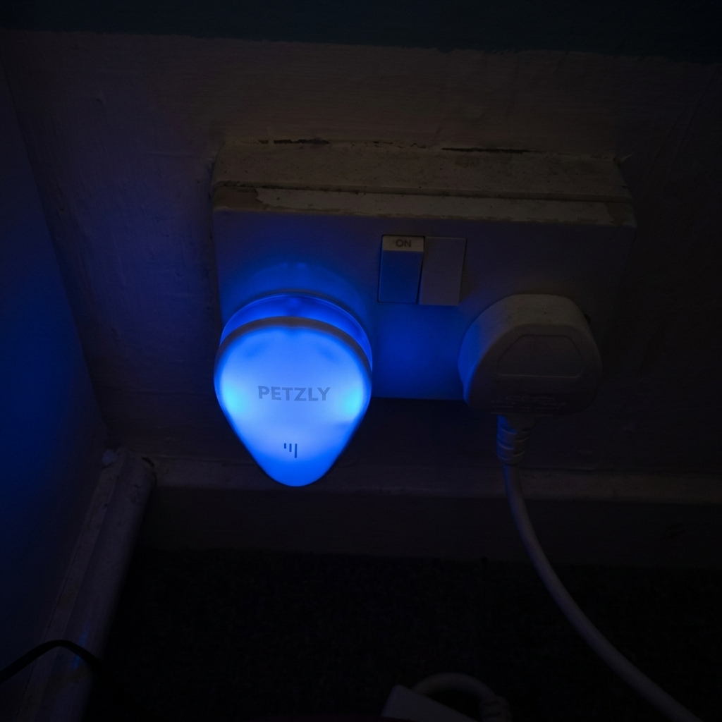 Ultrasonic pest repeller glowing blue in a wall socket at night