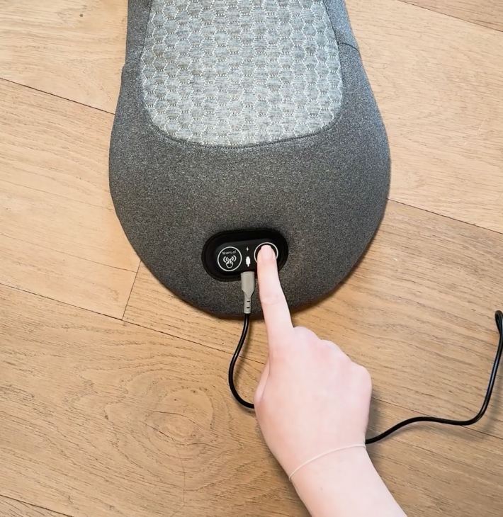 Finger pressing the power button on the massager