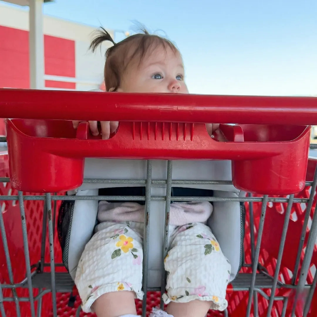 Baby sitting in the padded seat in a shopping cart child seat