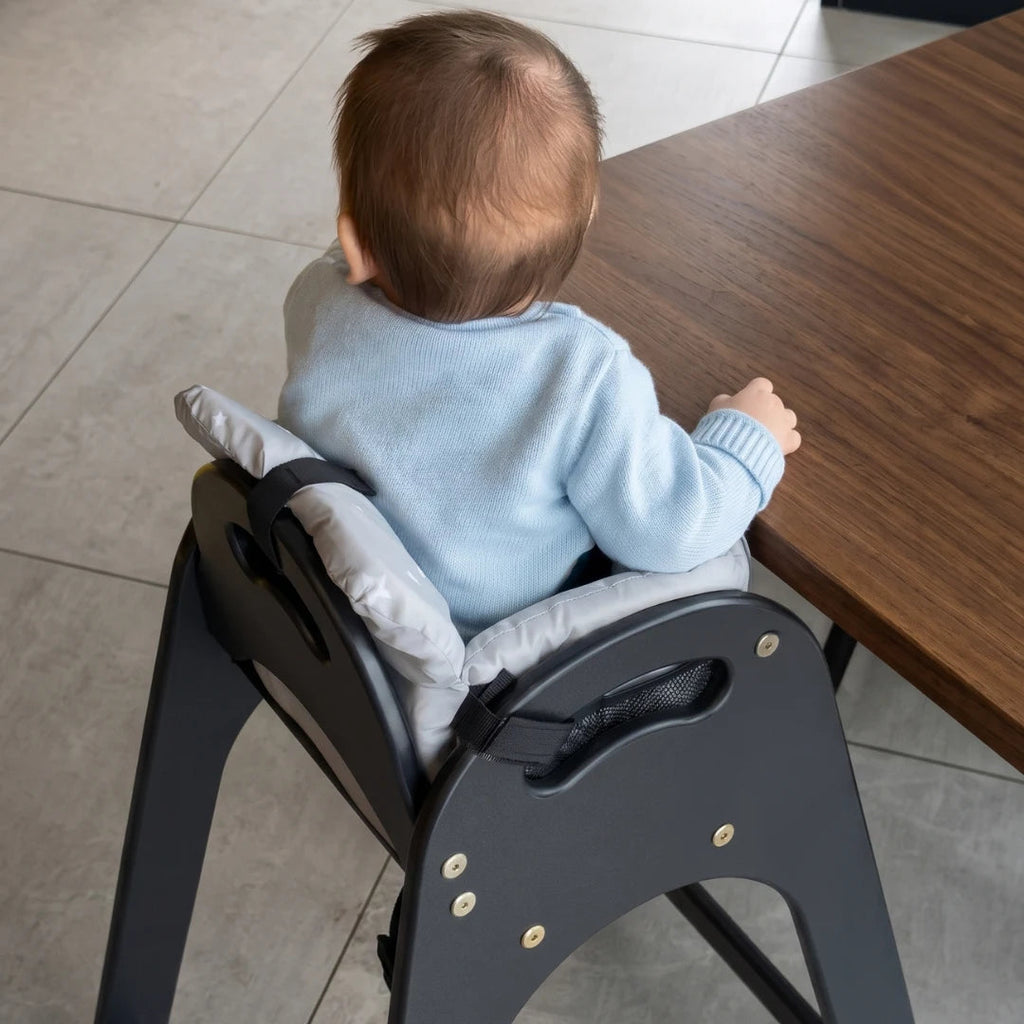 Baby at the table in a high chair with the grey padded seat
