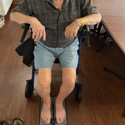 Seated man with his feet on the EMS mat at home
