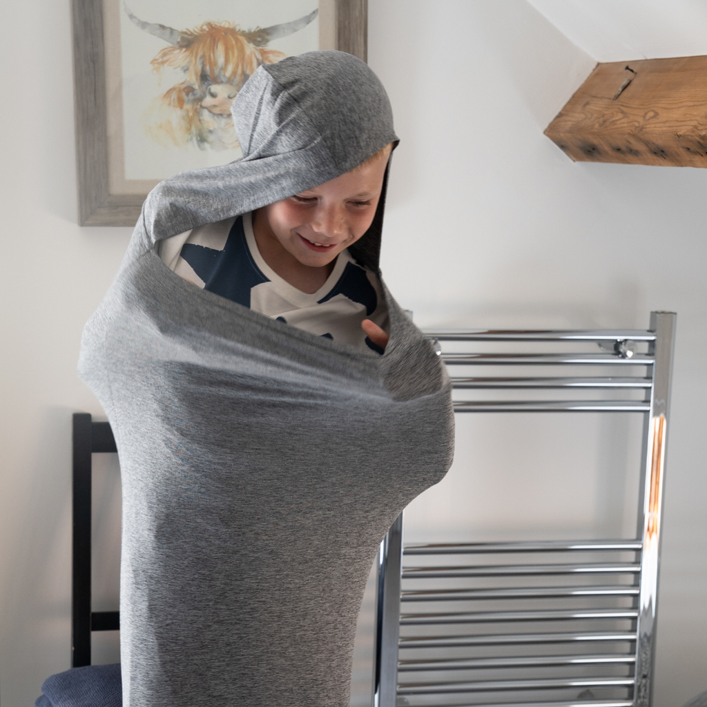Boy pulling a gray sensory pod over his head