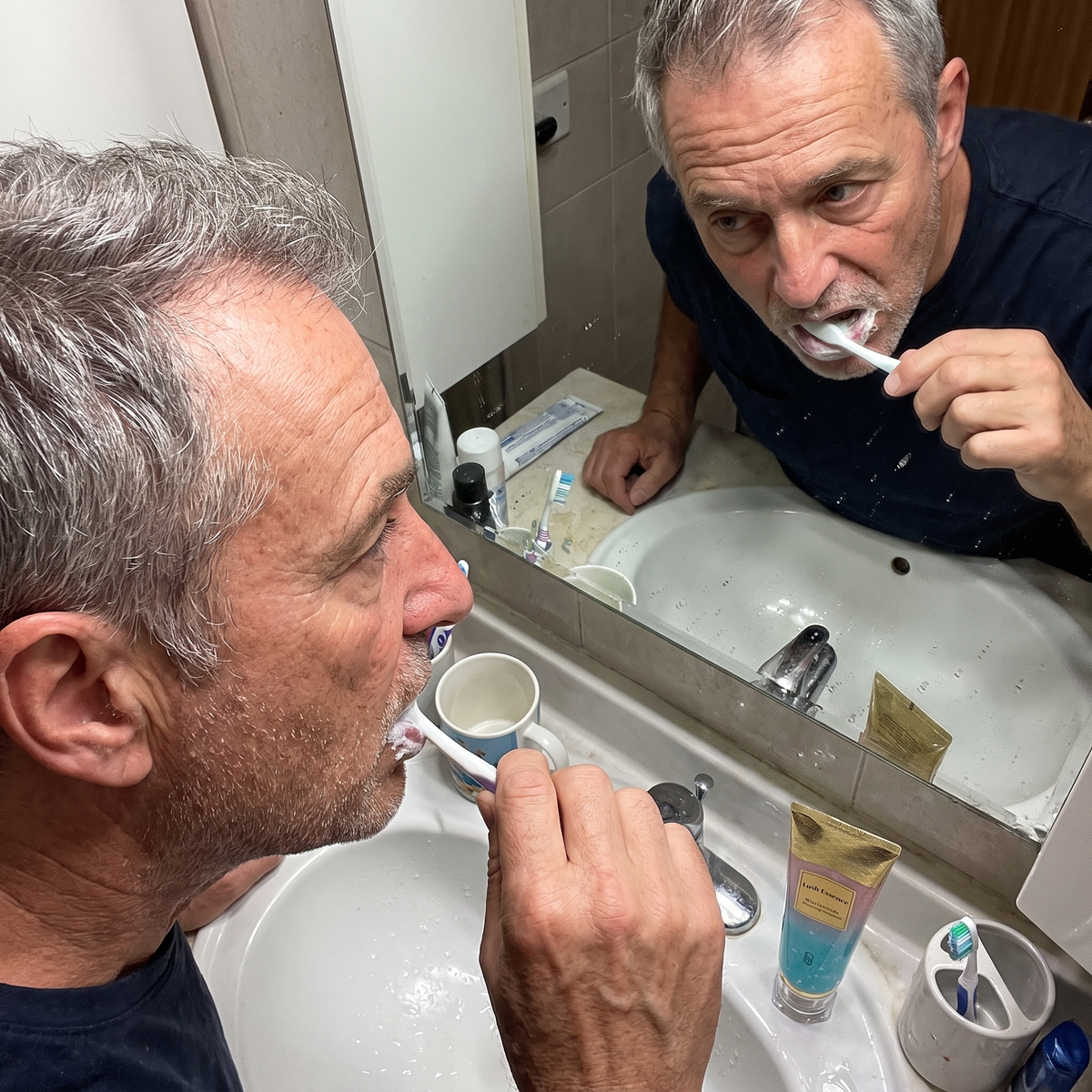 Man brushing his teeth at the bathroom sink