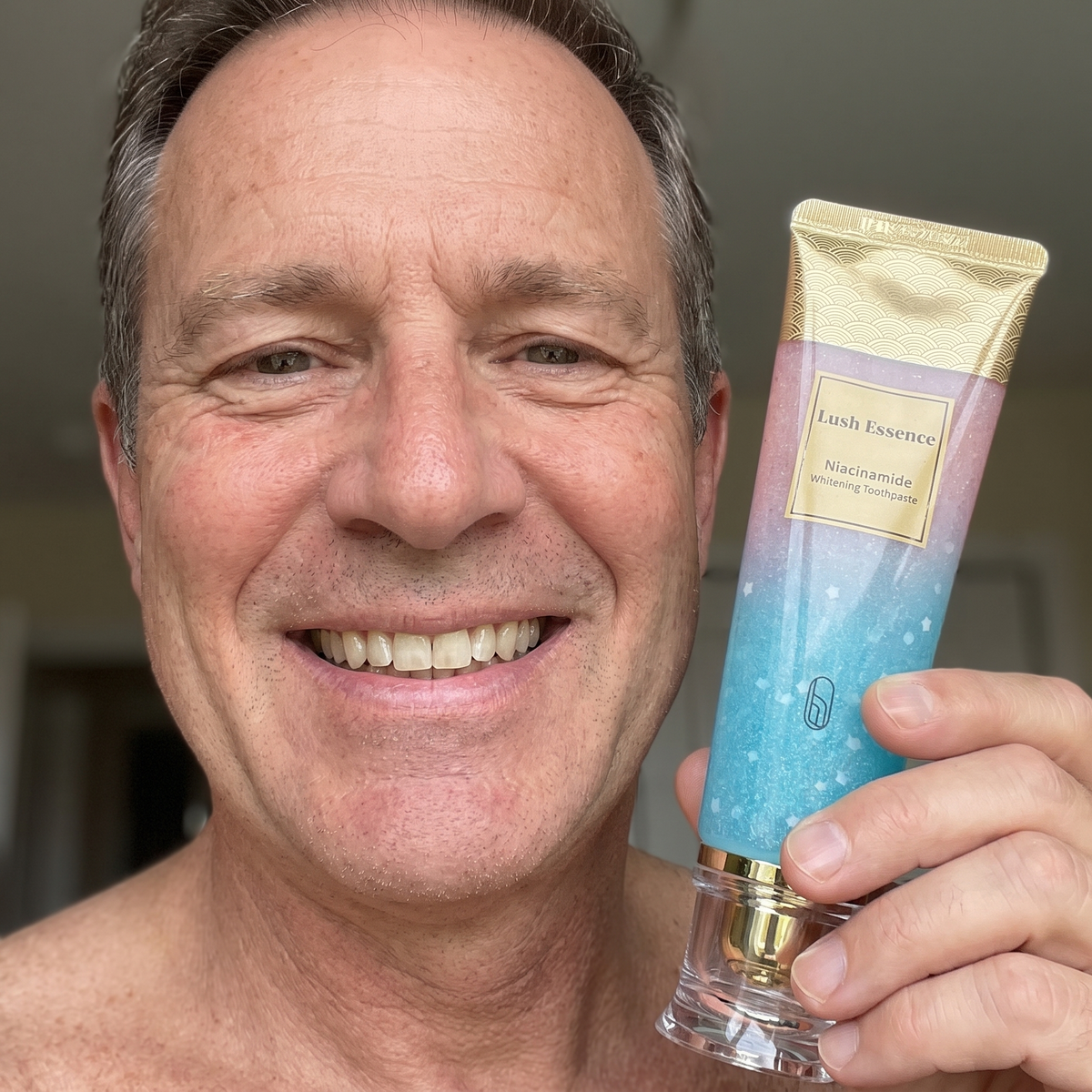 Smiling man showing the toothpaste tube