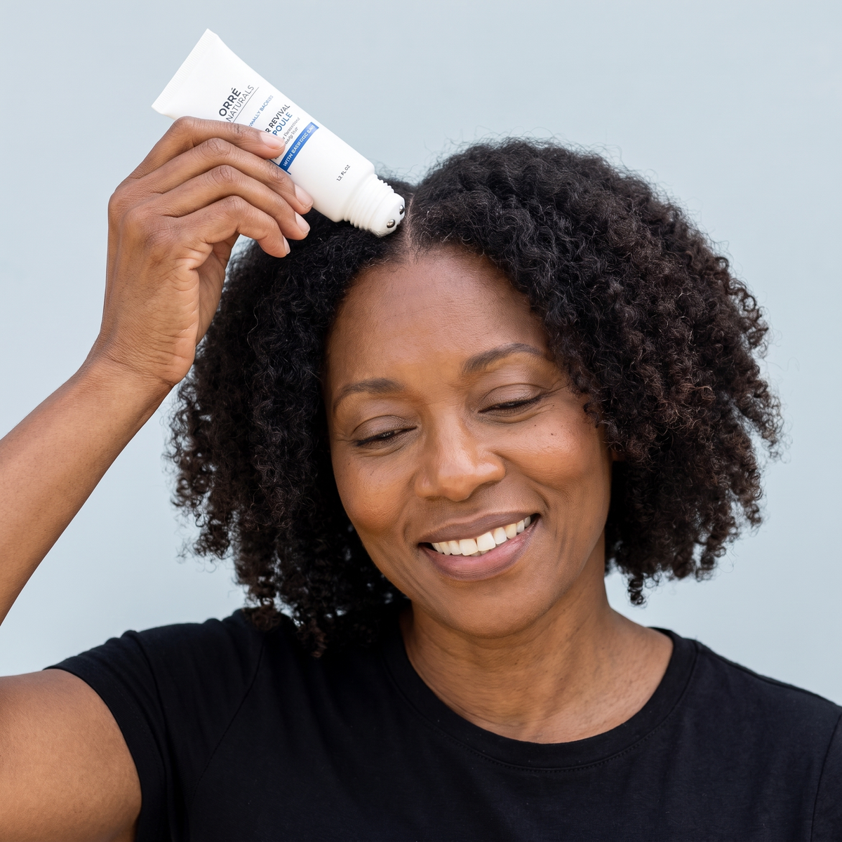 Smiling woman rolling the ampoule along her scalp
