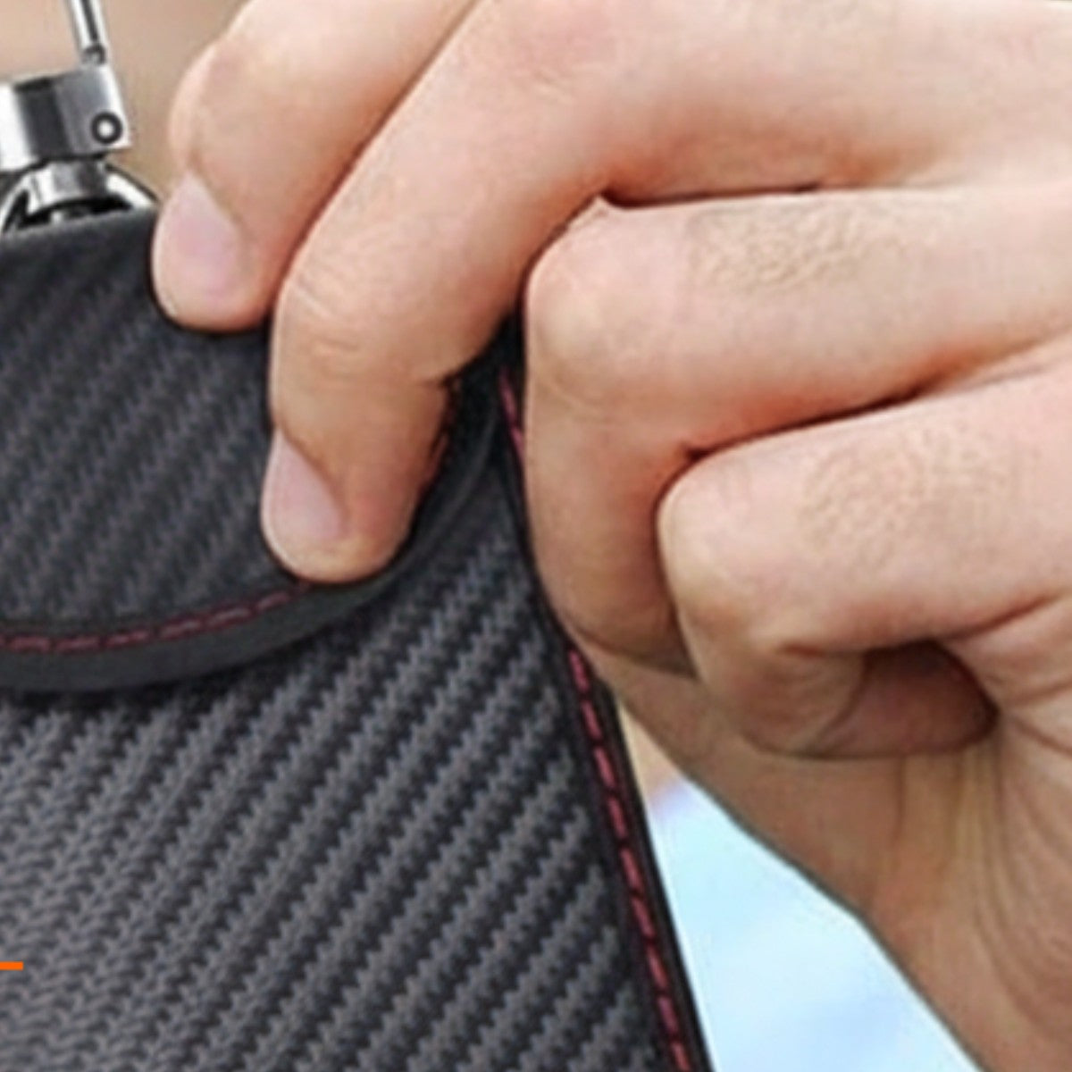 Hand holding the Faraday key pouch by its clip