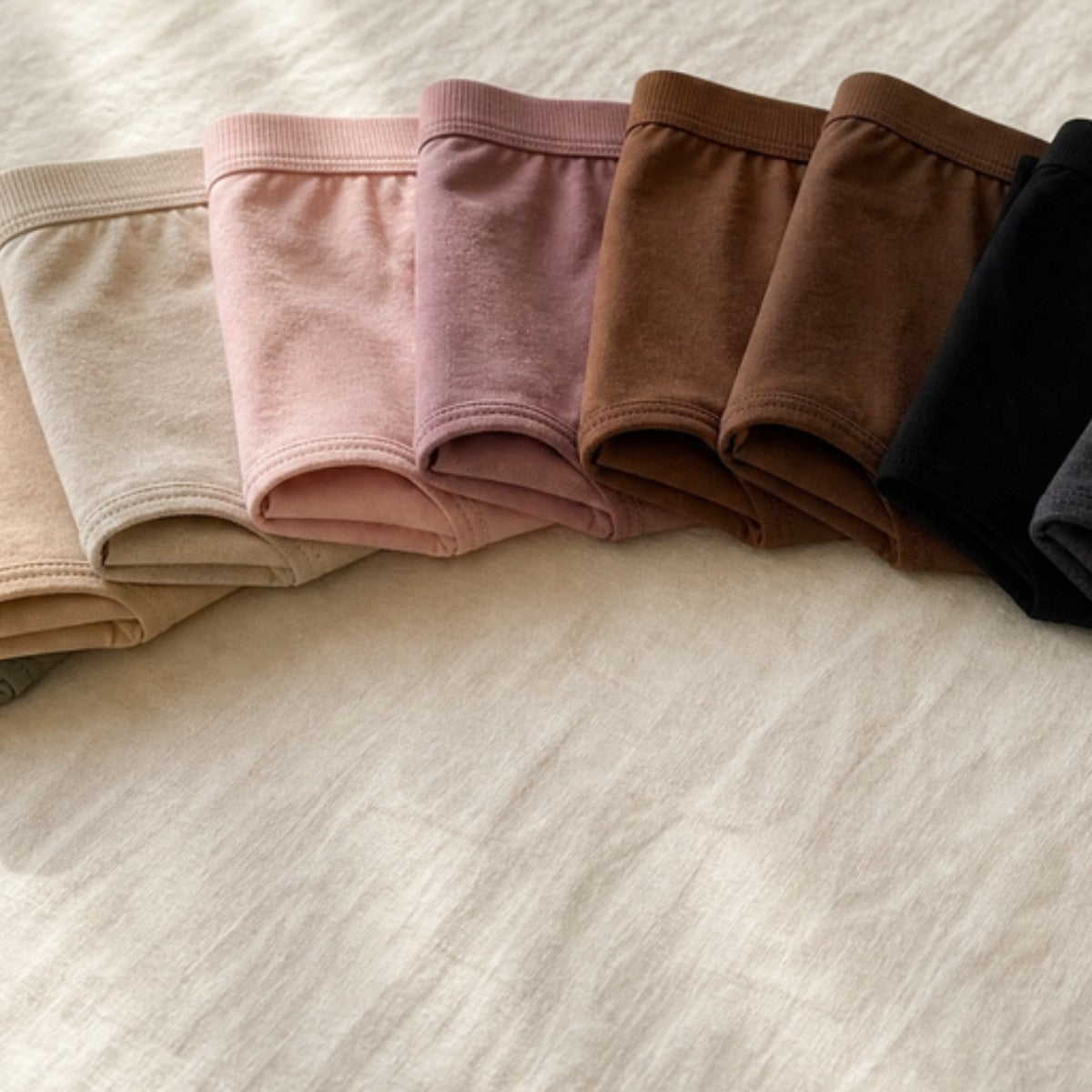 Leakproof underwear colour range laid out on the bed
