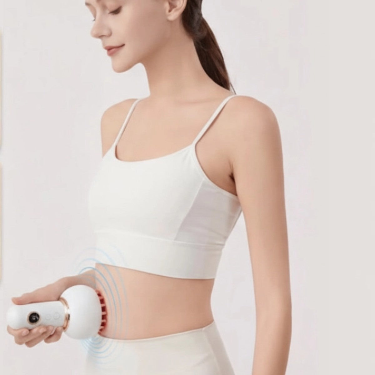 Woman holding the body massager against her abdomen