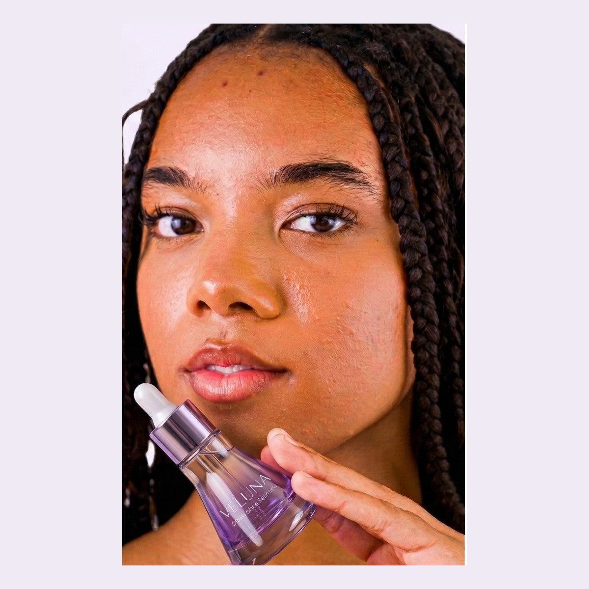 Woman holding Veluna serum bottle near her face