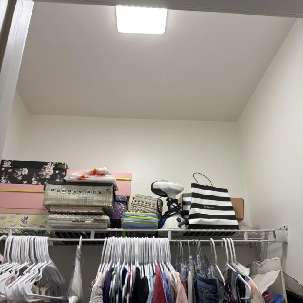 Walk-in closet lit by a slim square light on the ceiling