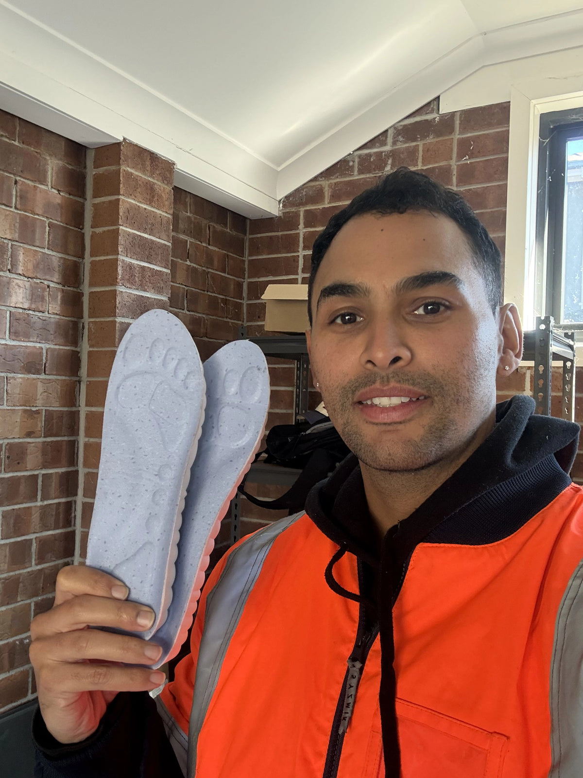 Worker in a hi-vis jacket holding up a pair of insoles