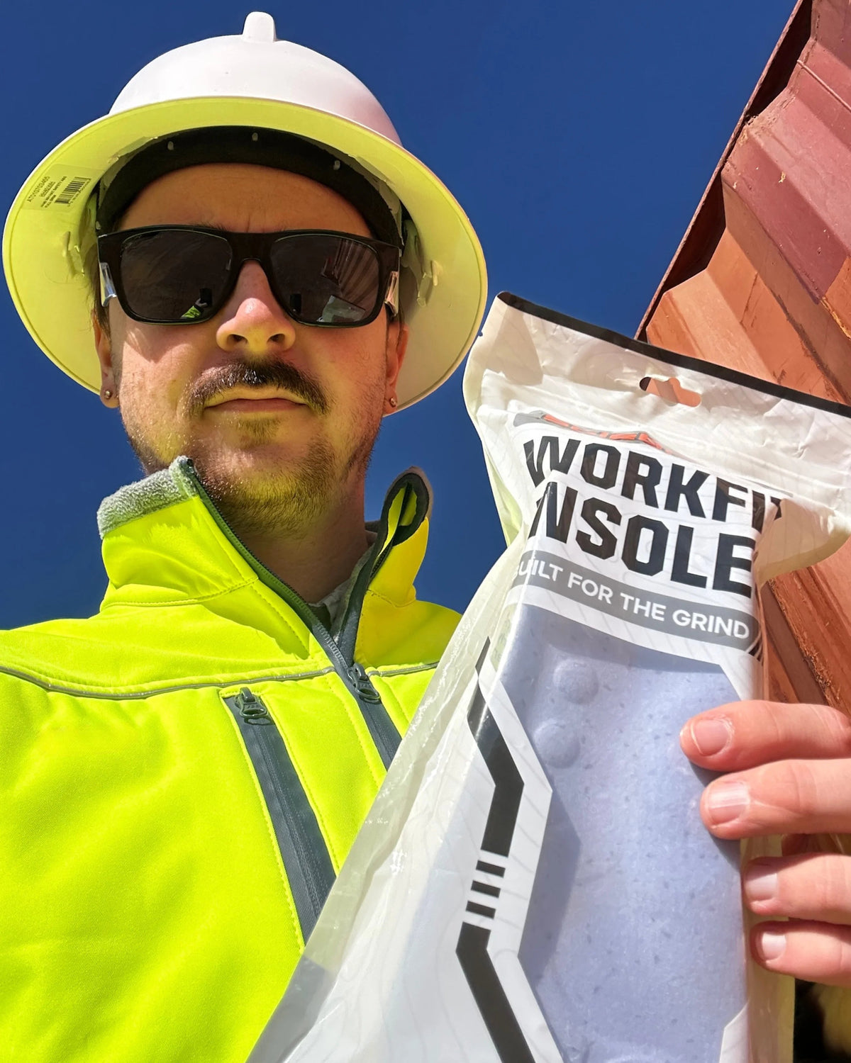 Site worker in a hard hat holding a pack of insoles