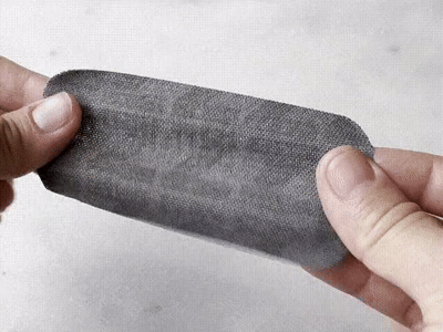 Hand holding a grey mouth tape strip to show the fabric texture