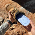 Hand slipping a blue insole into a work boot on a building site
